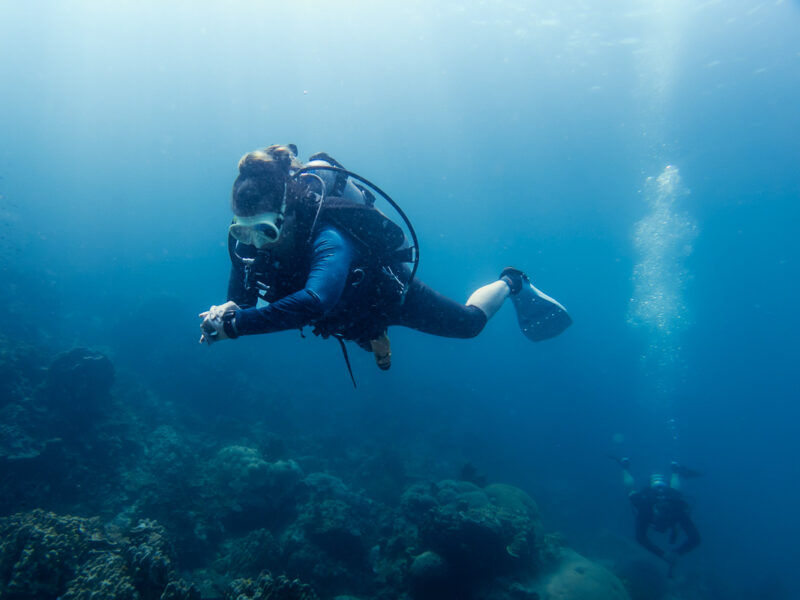 A diver using a compass to navigate the underwater dive site.