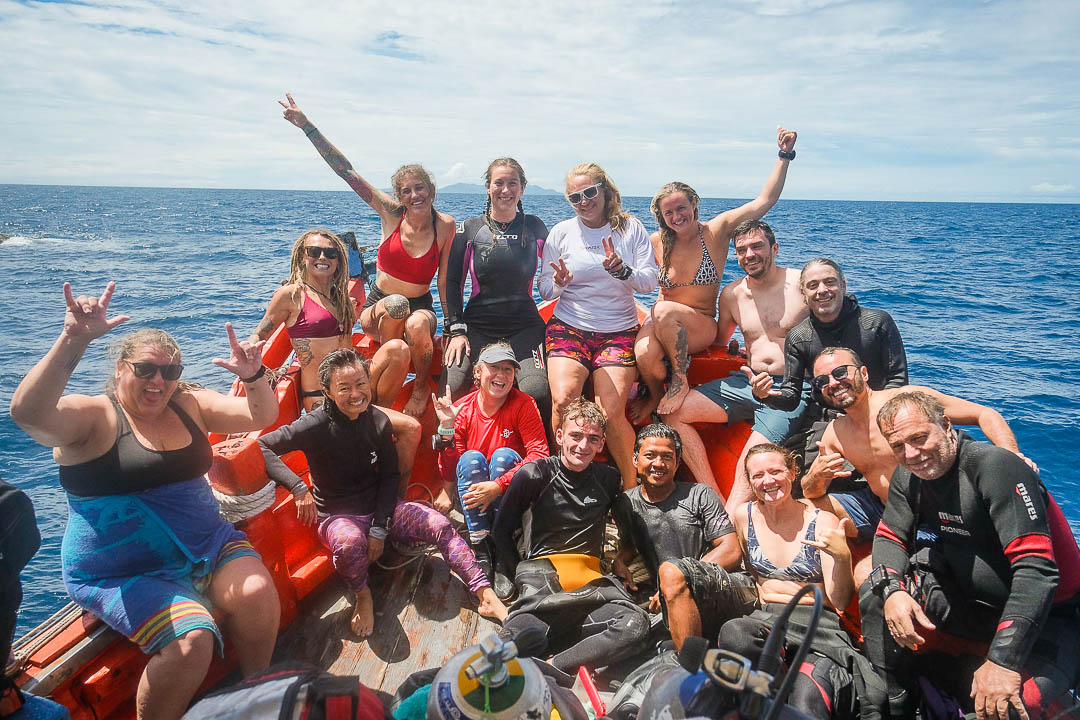 Group of smiling divers after a dive on the boat of the boat.